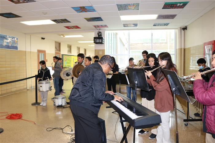 Mr Glenn at the keyboard with the winds section